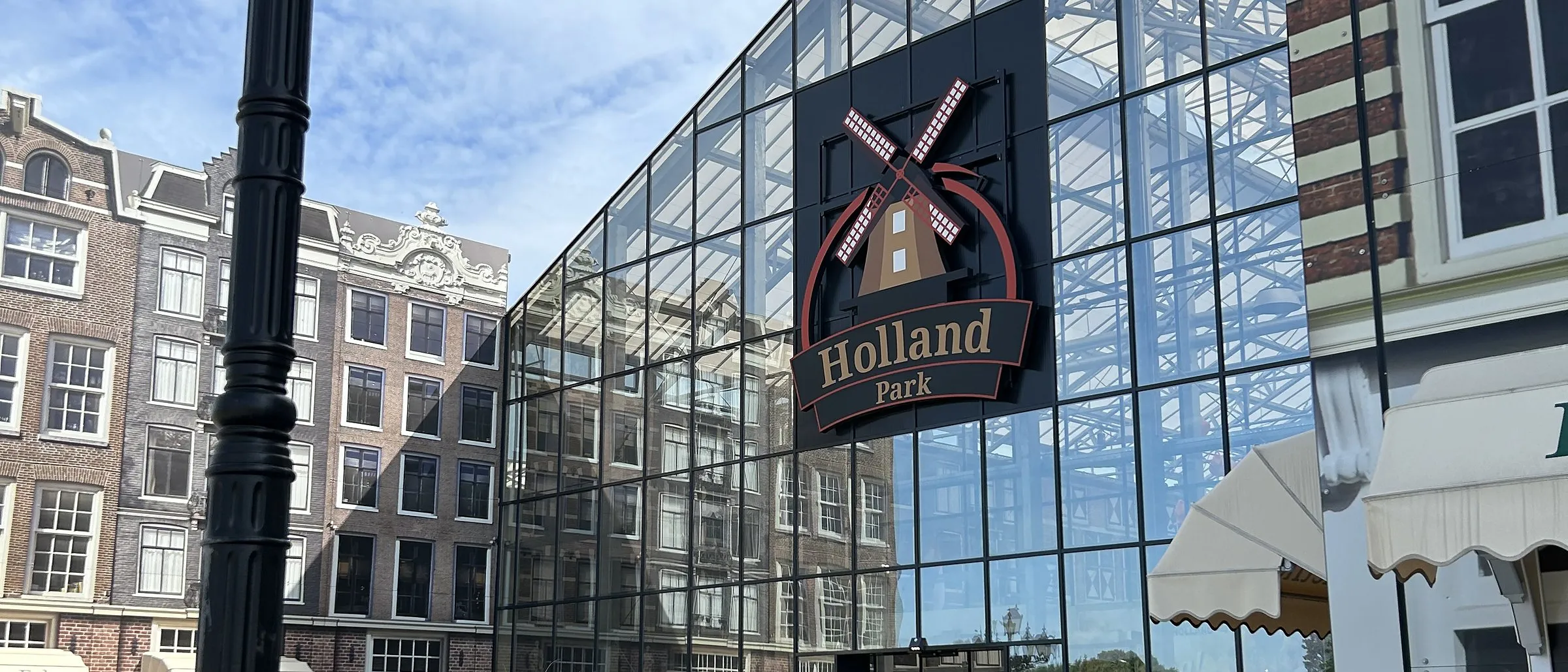 Holland Park Panketal: Eingang der Glashalle mit Holland-Park-Schild zwischen Häuserfassaden im Amsterdamer Stil